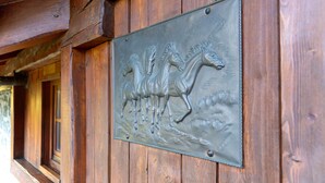 Een houten wand met een metalen plaquette waarop een paard staat afgebeeld.