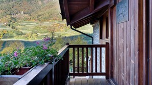 Een houten balkon met uitzicht op een bergachtig landschap en terrassen.