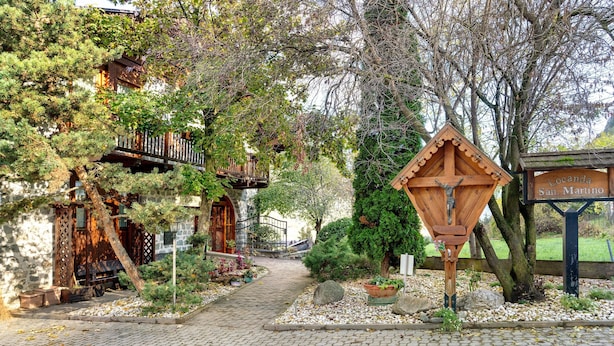 A cobblestone pathway leading to a wooden building with a sign reading 'Locanda San. Martino.'