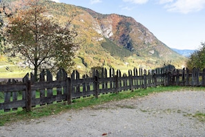 Un chemin de gravier, une clôture en bois et un paysage montagneux.