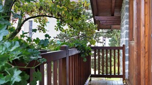 A wooden balcony with a view of a building and trees.
