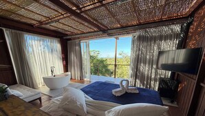 Un dormitorio con una cama grande, una bañera, televisión y un balcón con vistas.