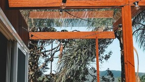 Una estructura de pérgola de madera con vistas a la vegetación tropical y colinas distantes.