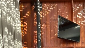 Una estufa de leña en una habitación con una pared de madera y un televisor montado.