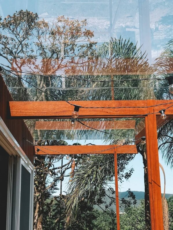 Una estructura de pérgola de madera con vistas a la vegetación tropical y colinas distantes.