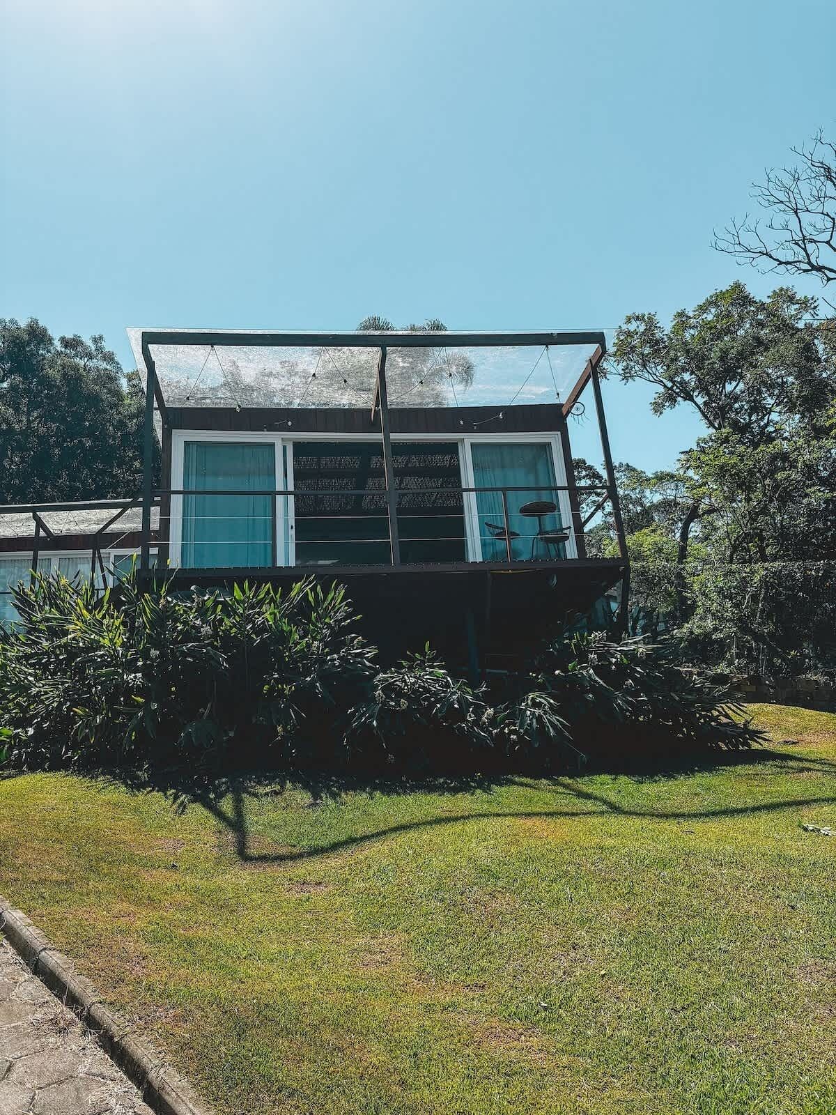 A modern building with a glass facade, surrounded by greenery.