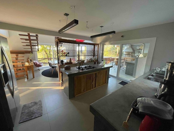 A modern kitchen with a central island, built-in appliances, and a dining area with a view.