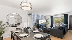 A modern living room with a dining area, a large mirror, and a view of the outdoors.
