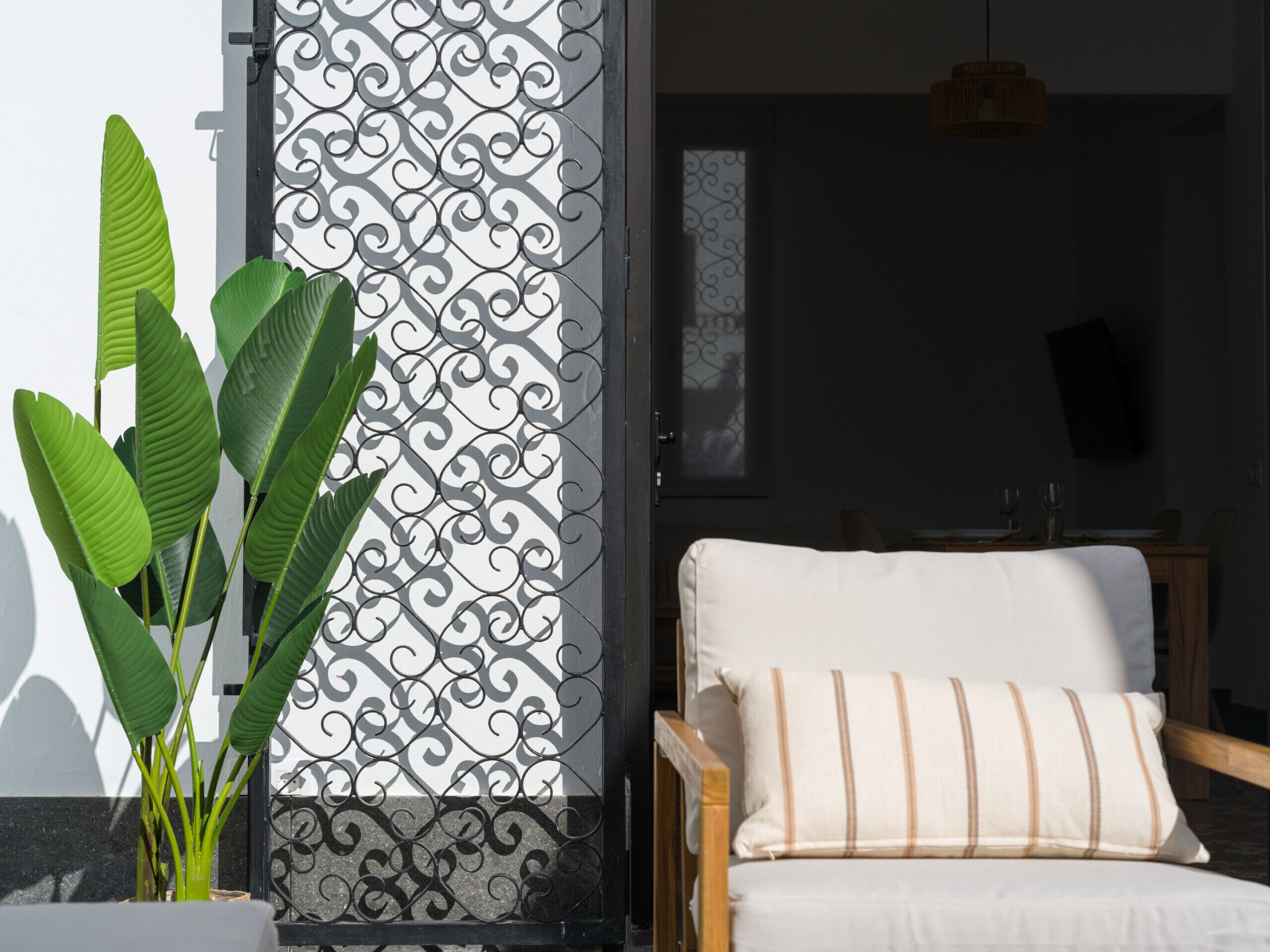 A room with a white chair, a decorative metal gate, and a potted plant.