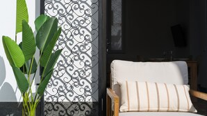 Ein Zimmer mit einem weißen Stuhl, einem verzierten Metallgitter und einem Blumentopf.