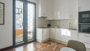 Eine moderne Küche mit weißen Schränken, einem schwarzen Backofen und einem Essbereich mit Tisch für zwei Personen.