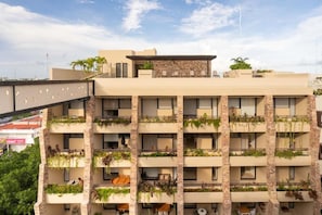 A multi-story building with balconies, some with plants.