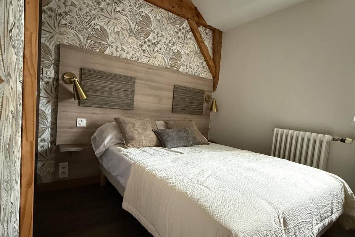 Un dormitorio con cabecera de madera, cama con ropa de cama blanca y un radiador en la pared.