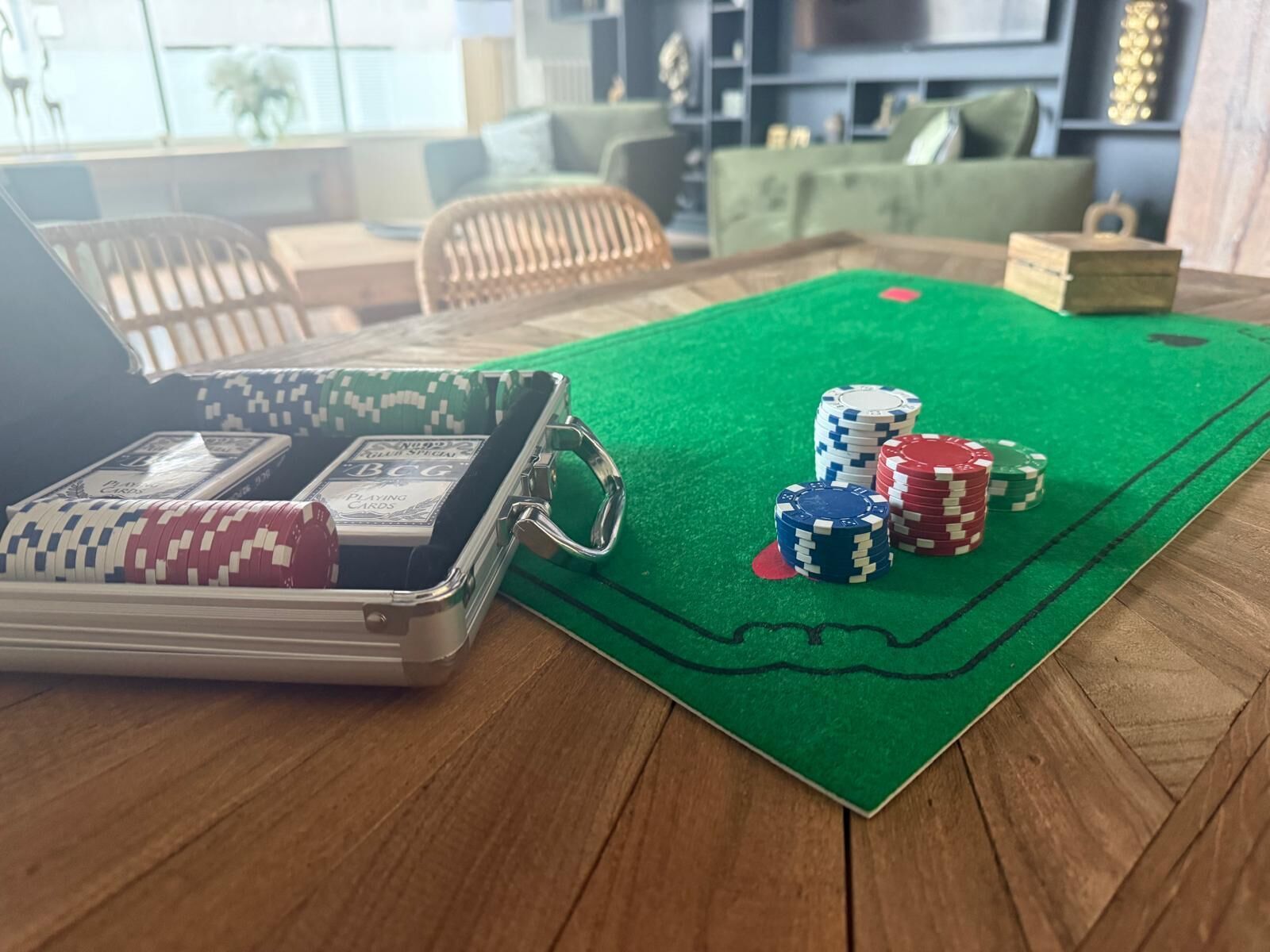 Una mesa de póker con superficie de fieltro verde, una pila de fichas de póker y una baraja de cartas.