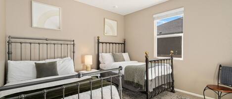 Un dormitorio con dos camas, una ventana y una silla.