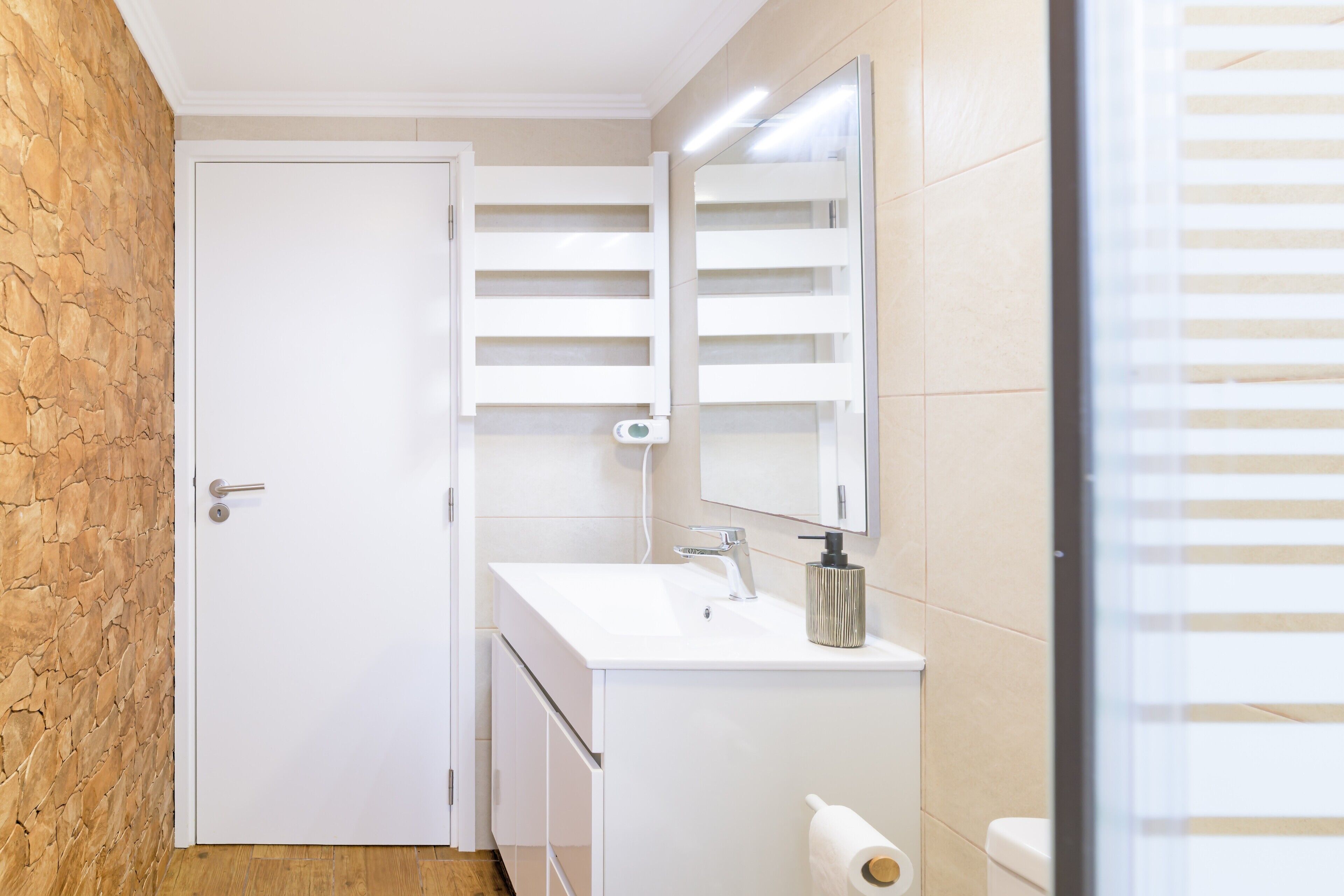 Un baño con lavamanos, espejo y retrete blancos.