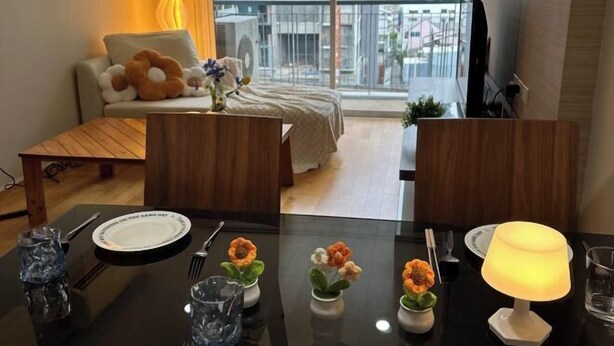 A modern living room with a sofa, a coffee table, and a dining table set with plates, cutlery, and flower vases. - Villa Ratchatewi 5 STARS suite l 4 mins walk BTS&APL (Bangkok)