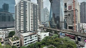 A high-rise building with a modern glass facade, surrounded by other buildings and a busy street with a pedestrian bridge overhead. - Villa Ratchatewi 5 STARS suite l 4 mins walk BTS&APL (Bangkok)