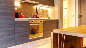 A modern kitchen with wooden cabinetry, a built-in oven, and a red kettle.