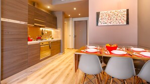 A modern kitchen with wooden cabinets, a dining table set for four, and a fruit bowl on the table.