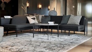 A modern living room with a dark-colored sofa, a round coffee table, and a patterned rug. - Four Points Flex by Sheraton Lyngby (Lyngby-Taarbaek Municipality)