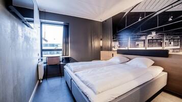 Una habitación de hotel moderna con una cama grande, un escritorio y vistas a la ciudad.