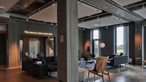 Un intérieur moderne aux couleurs sombres, agrémenté d’un néon et composé de différents espaces de détente.