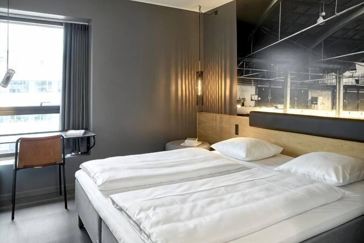 Een moderne hotelkamer met een groot bed, een bureau en een stoel.