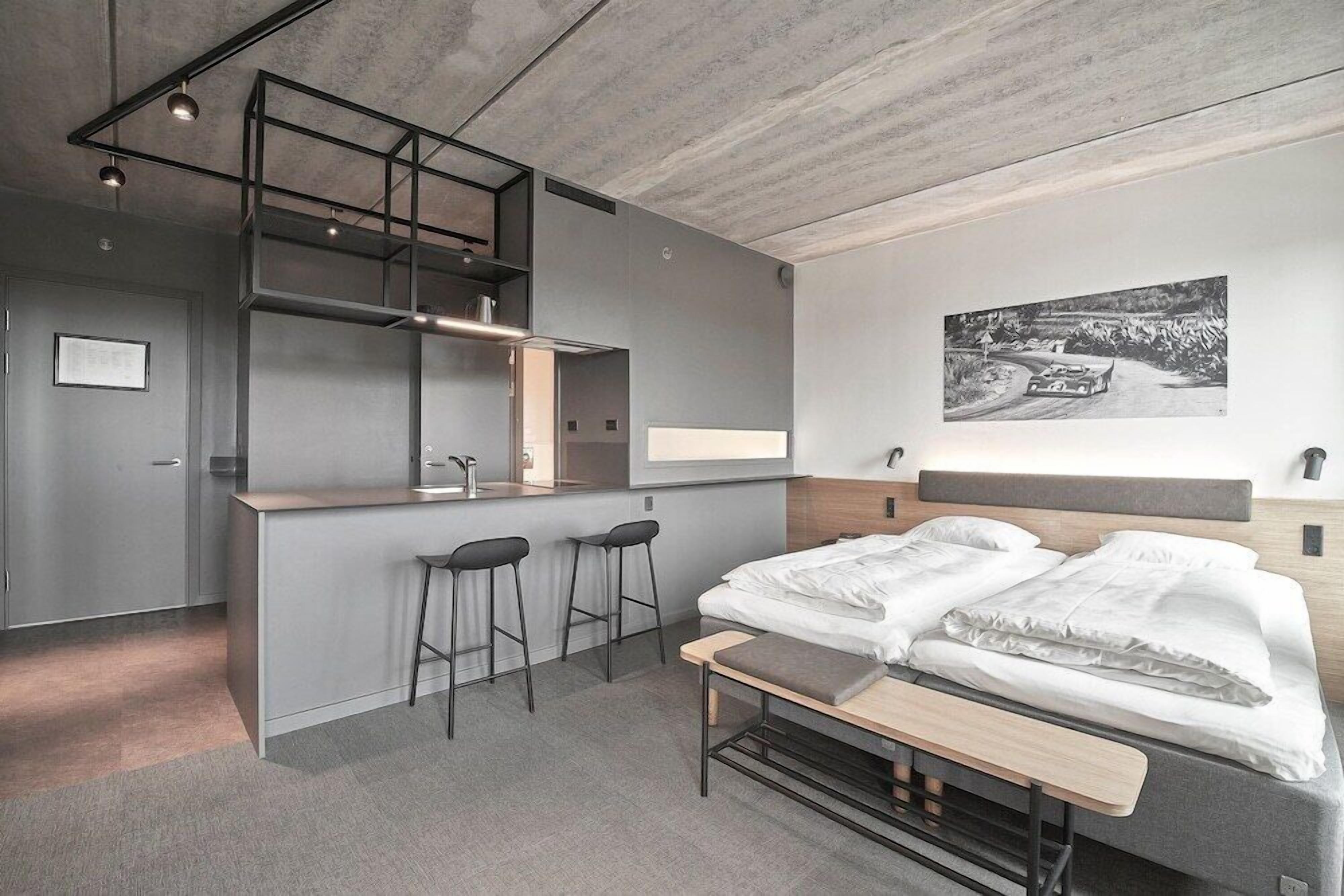 Una habitación de hotel moderna con cama, una kitchenette pequeña y una zona de bar.
