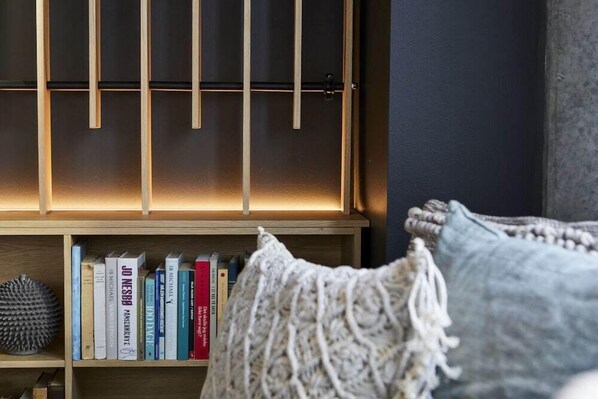 A bookshelf with books and a knitted throw blanket. - Four Points Flex by Sheraton Lyngby (Lyngby-Taarbaek Municipality)