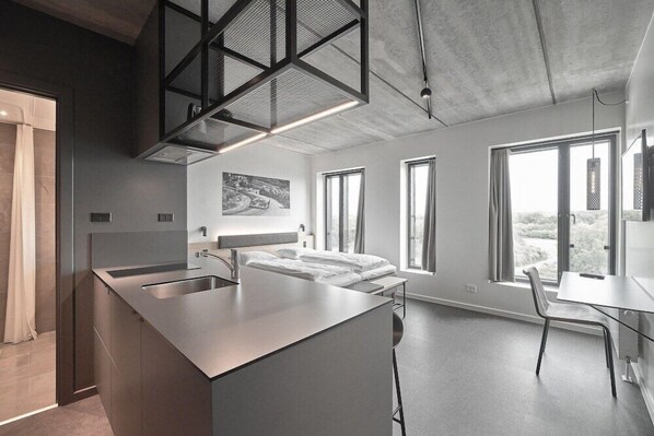 Una cocina moderna con una isla central, un comedor con mesa y sillas, y ventanas amplias con vistas.