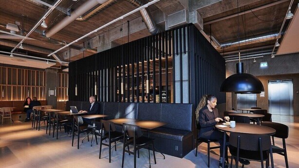 A modern interior with a central black partition, tables, and chairs arranged for dining. - Four Points Flex by Sheraton Lyngby (Lyngby-Taarbaek Municipality)