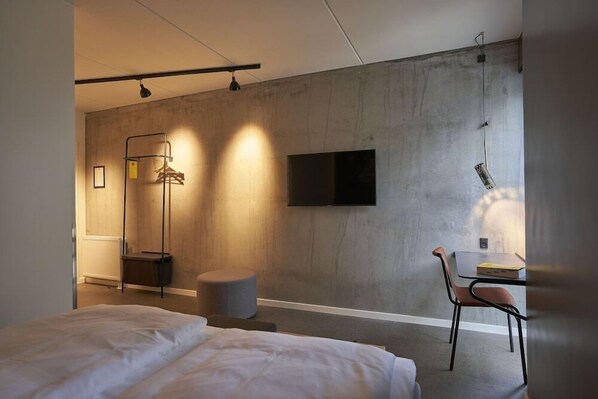 Une chambre d’hôtel moderne équipée d’un grand lit, d’un bureau avec une chaise, d’une télévision et d’une armoire.