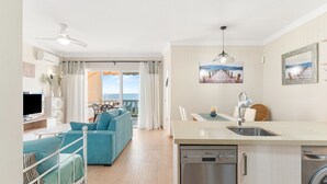 A modern living room with a sofa, a dining area with a table and chairs, a kitchen with a dishwasher, and a balcony with a view. - 'Apartamento Boquerón I' with Sea Views, Wi-Fi and Air Conditioning (Sitio de Calahonda)
