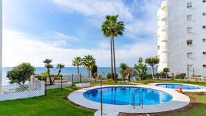 A pool area with two circular pools, surrounded by palm trees and a white building with balconies. - 'Apartamento Boquerón I' with Sea Views, Wi-Fi and Air Conditioning (Sitio de Calahonda)