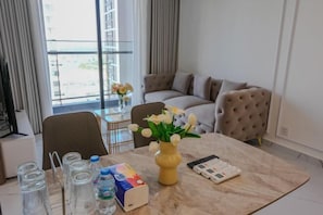 Habitación de hotel con una mesa de mármol, un florero, un sofá y vistas al exterior.