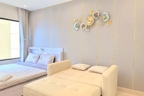 A bedroom with a bed, a sofa, and a wall clock.
