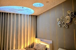 Una habitación con una cama, un reloj de pared y una lámpara en el techo.