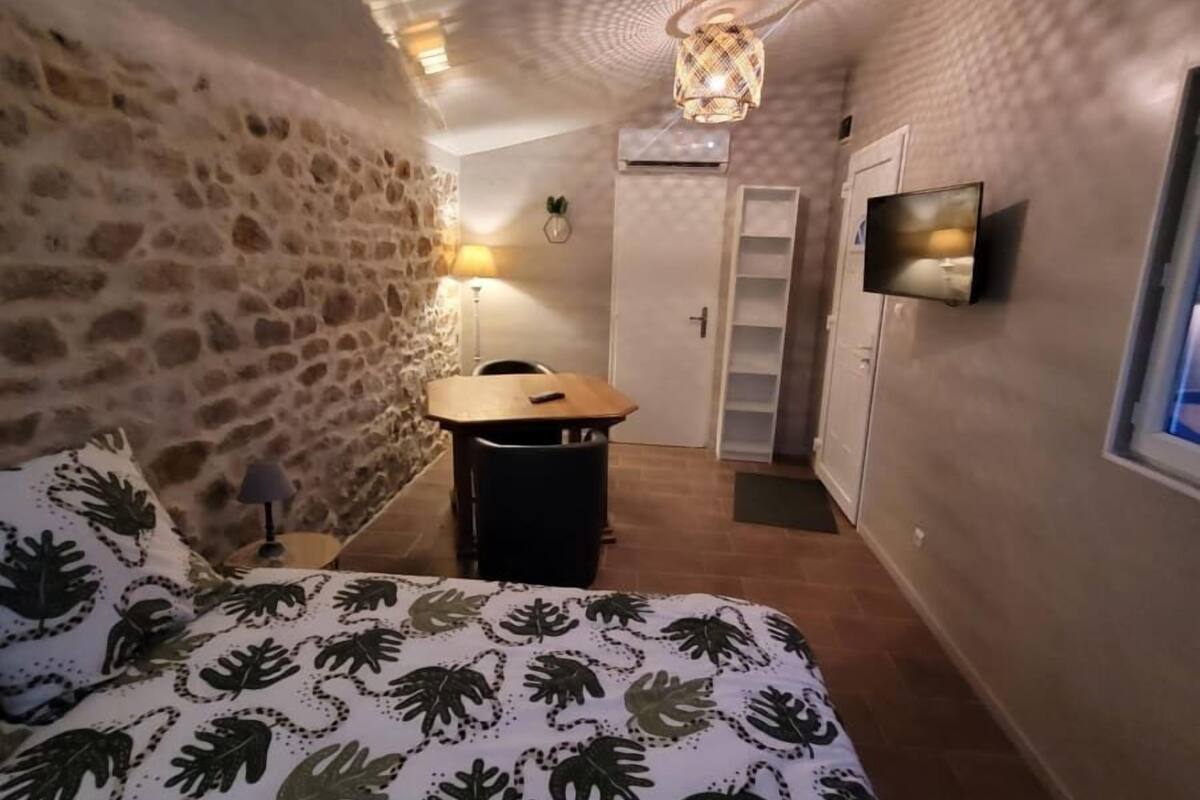 A bedroom with a bed, a desk, a chair, a TV, and a door.
