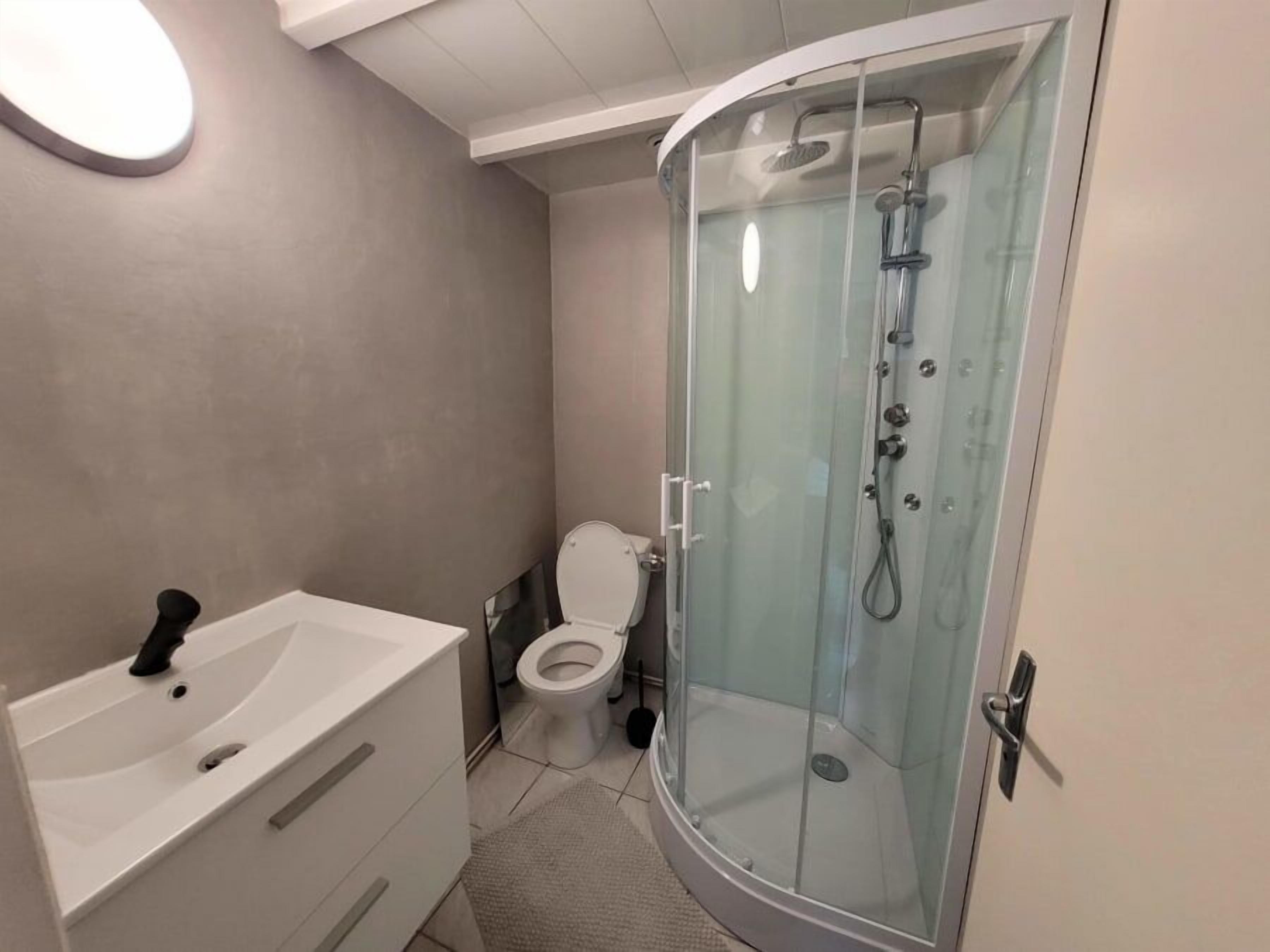 A modern bathroom with a glass-enclosed shower, a white sink, and a toilet.