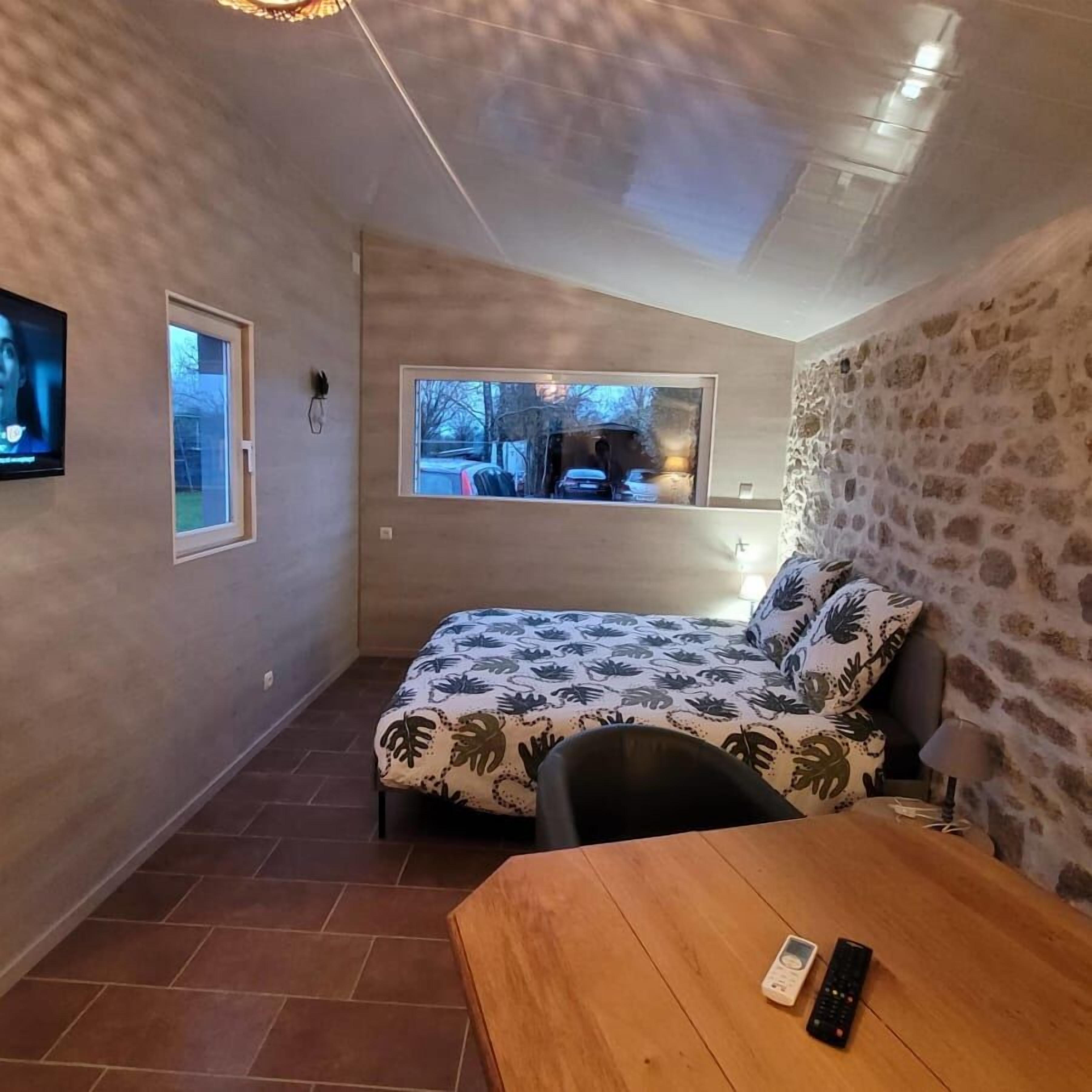 A small, cozy room with a bed, a wooden table, and a TV.