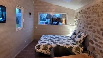 A small, cozy room with a bed, a wooden table, and a TV.