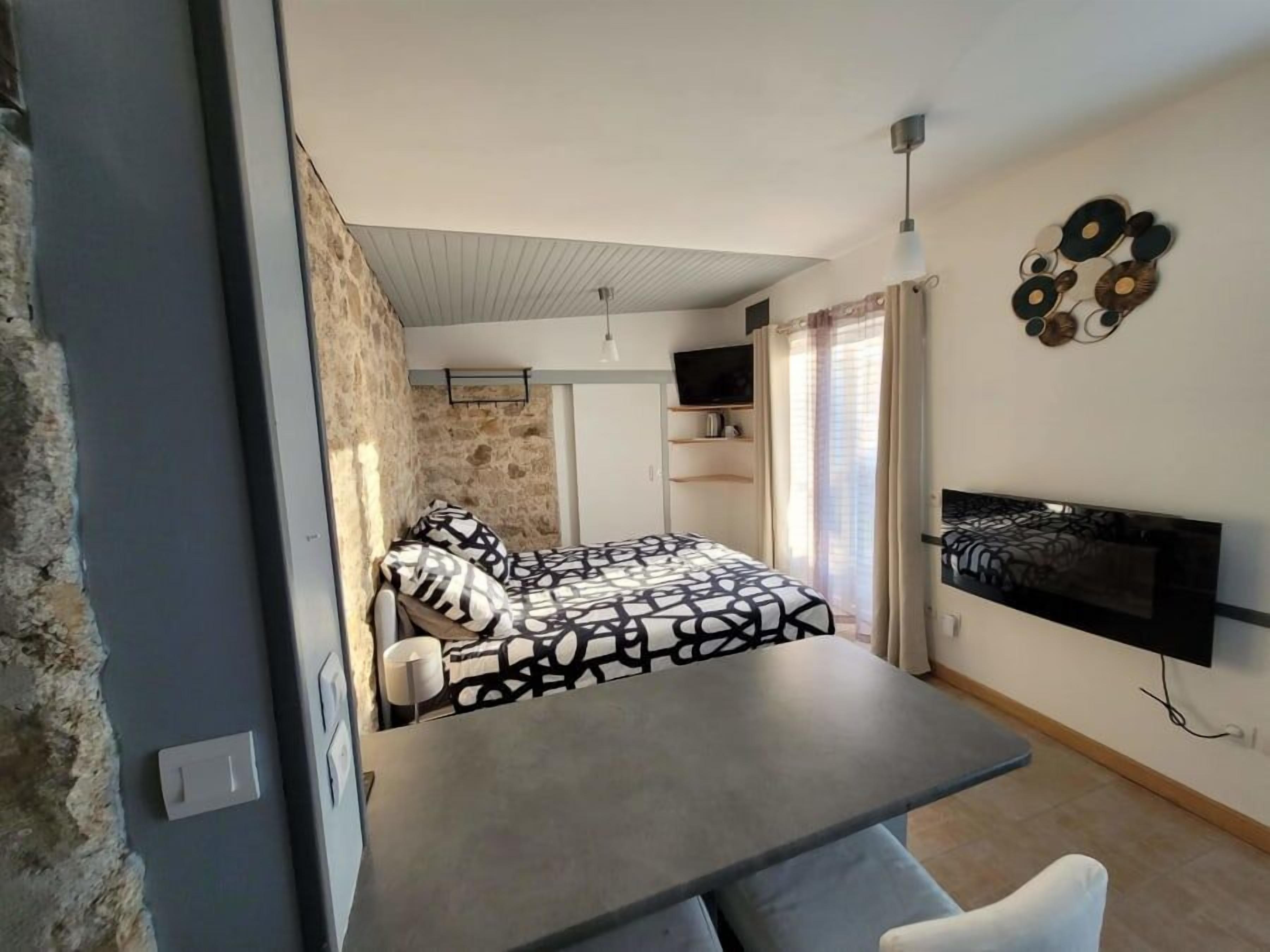 Ein modernes Schlafzimmer mit Bett, Fernseher und Essecke.