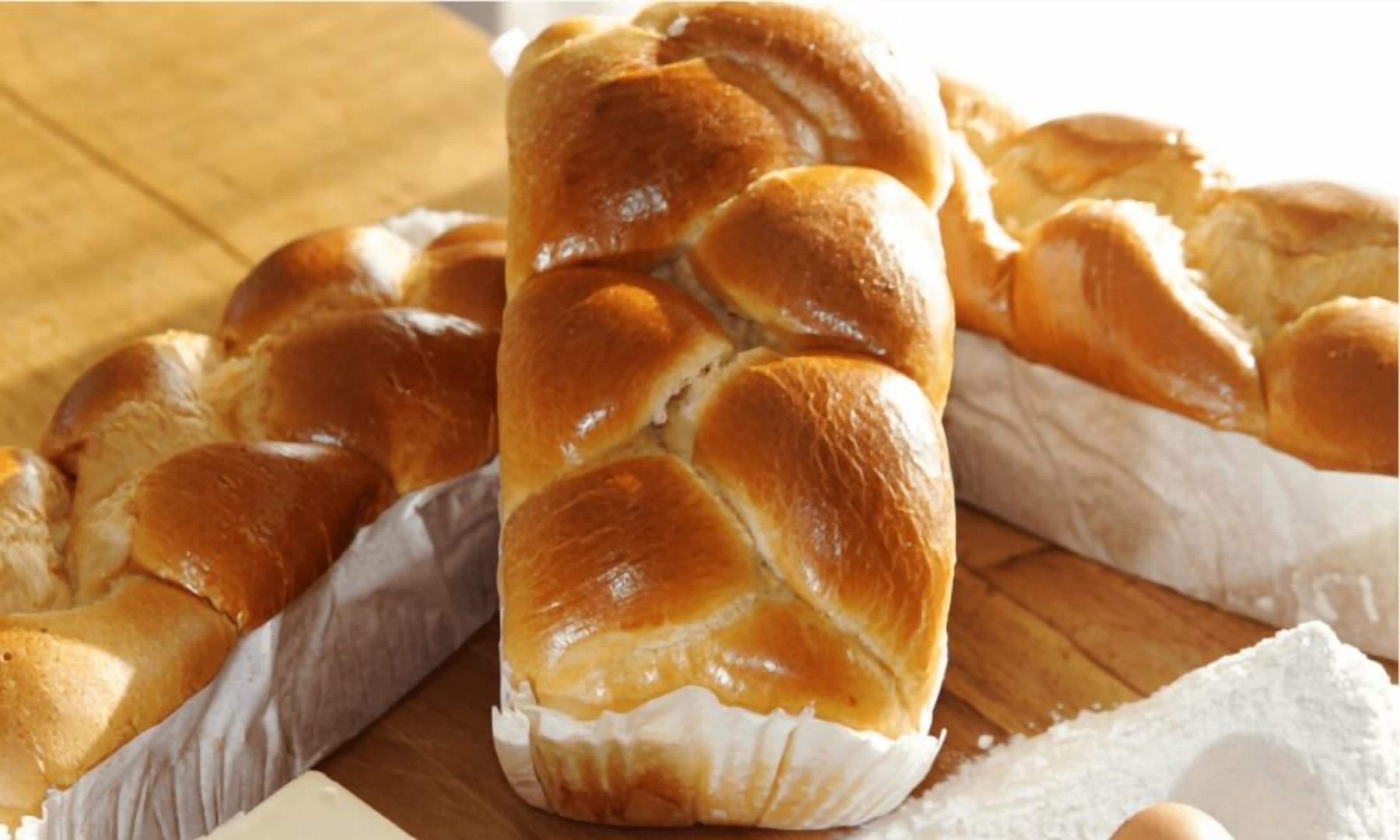 Een brood met een goudbruine korst, op een houten ondergrond.