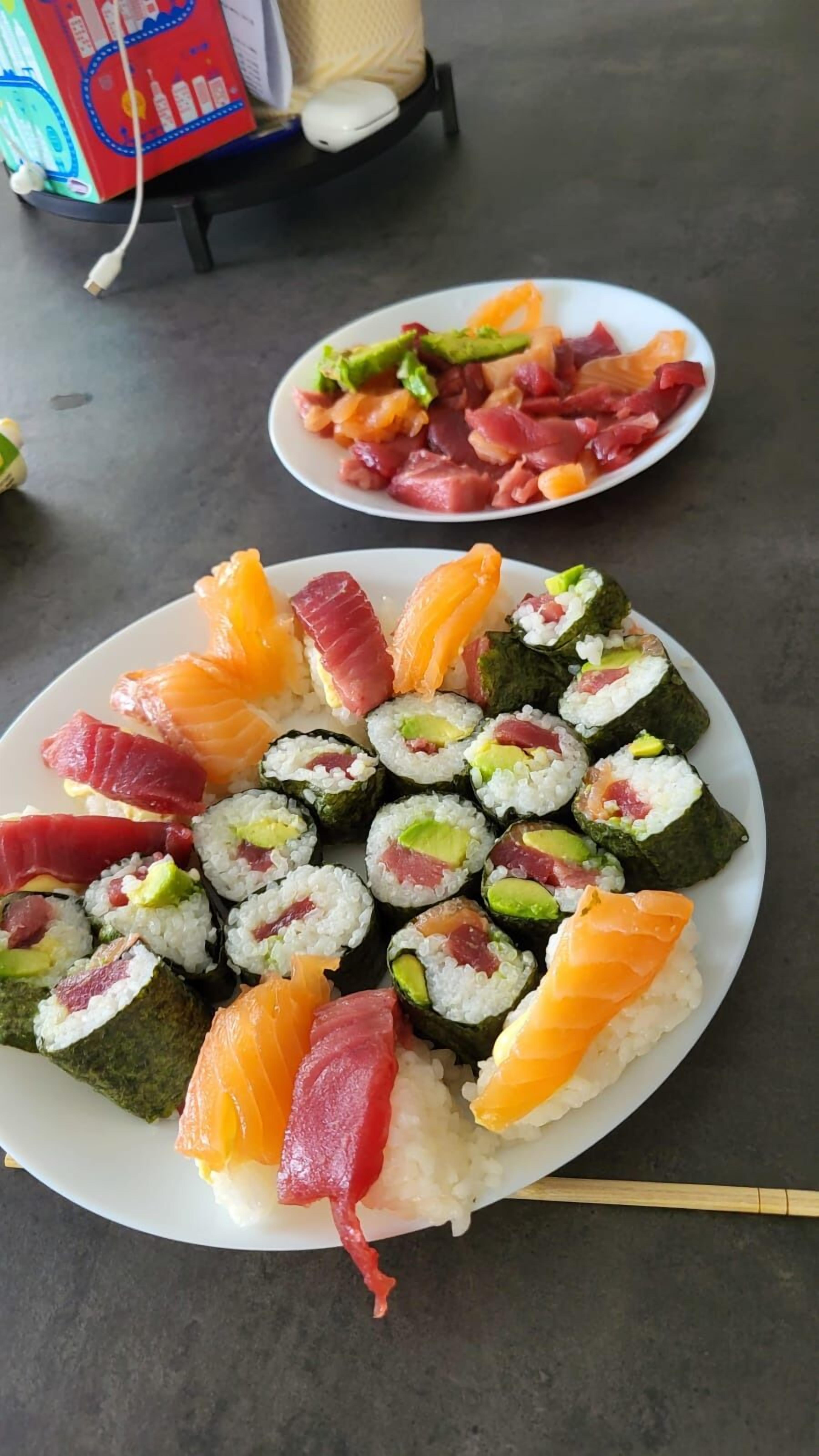 Two plates of sushi with various toppings, including salmon and avocado, on a table.