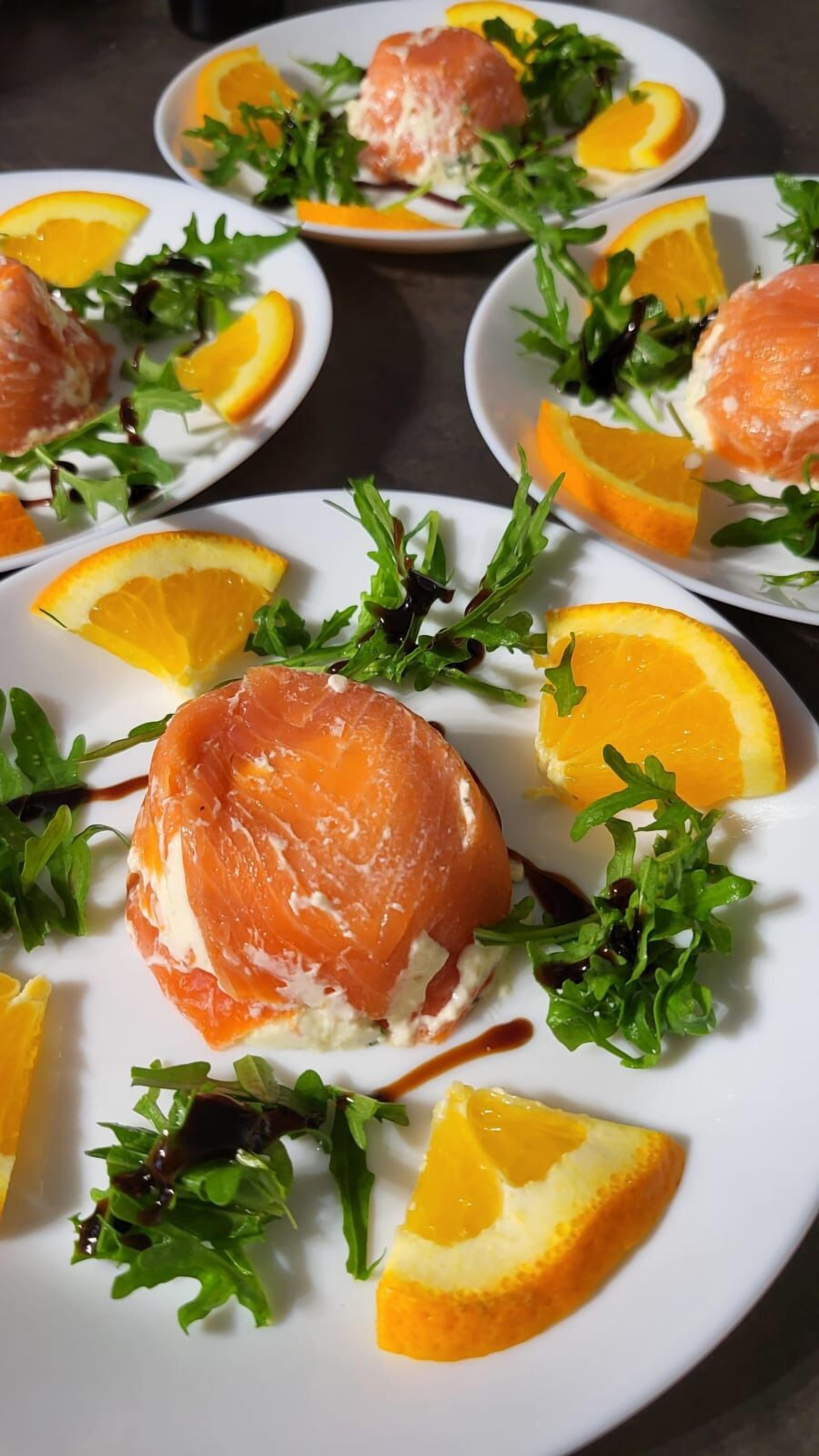 A table with plates of food, each containing salmon, greens, and orange slices.