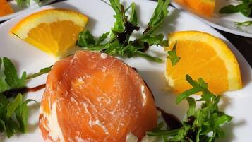 A table with plates of food, each containing salmon, greens, and orange slices.