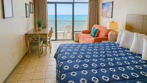 Een hotelkamer met een bed, een bureau, een stoel, een bank en uitzicht op de oceaan.