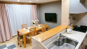 A compact kitchen with a built-in sink, wooden dining table, and chairs. - Xiao Ban Yaju (Osaka)