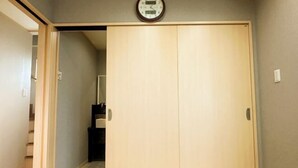 A wooden wardrobe with a clock above it, a door, and a visible staircase in the background. - Xiao Ban Yaju (Osaka)